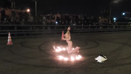 Голая девушка показывает фаер шоу и стриптиз на асфальте