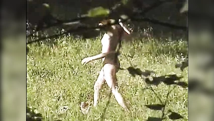 Нудистка собирает цветы на поляне